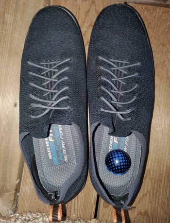 Reviewer photo of a pair of grey sneakers with a blue deodorizer ball in the right one 