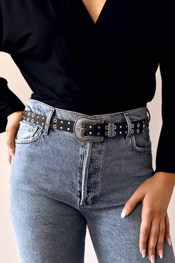 Model wearing studded belt in black with silver studs around the whole thing