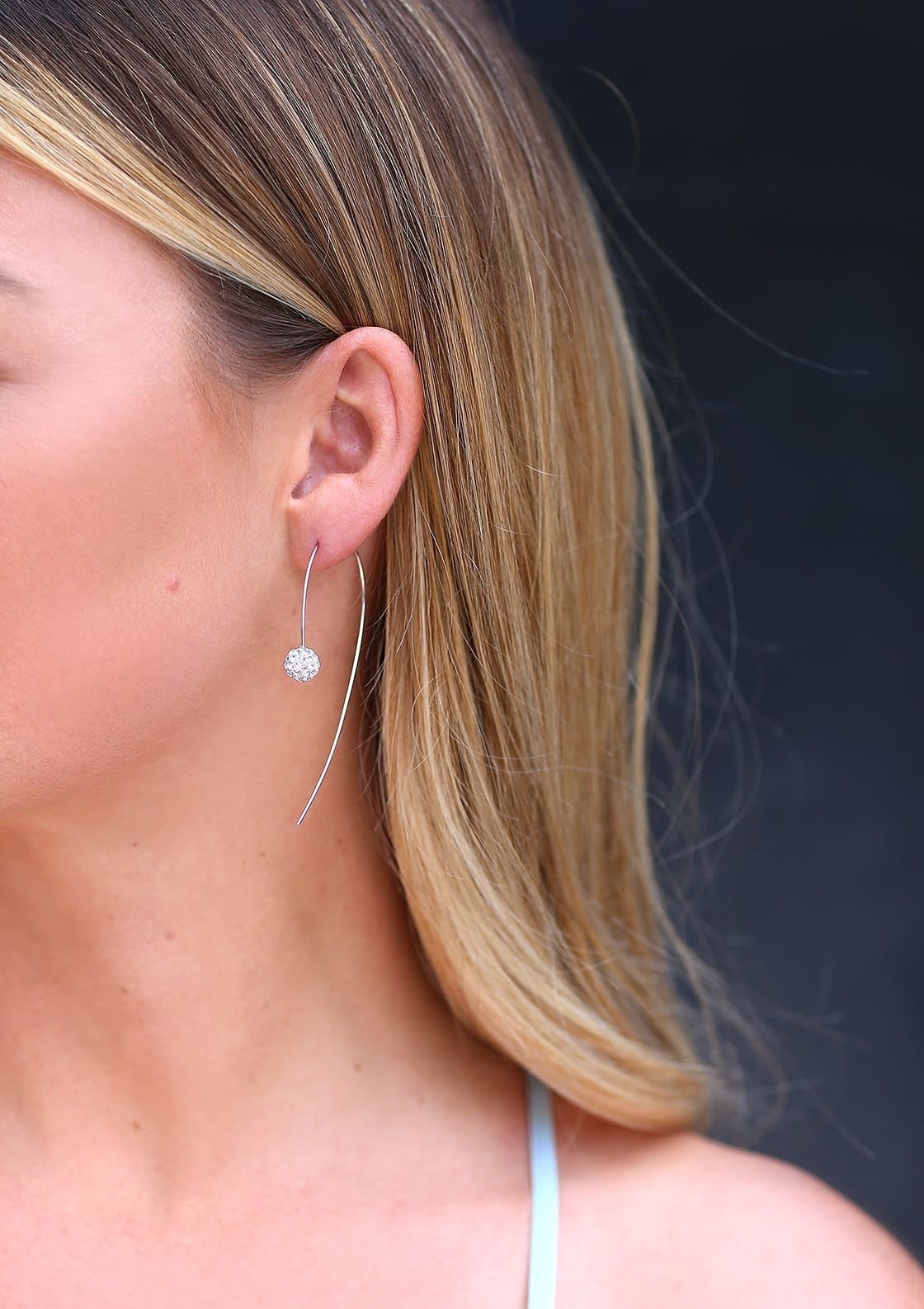 Model wearing silver threader earrings with a small rhinestone in the front