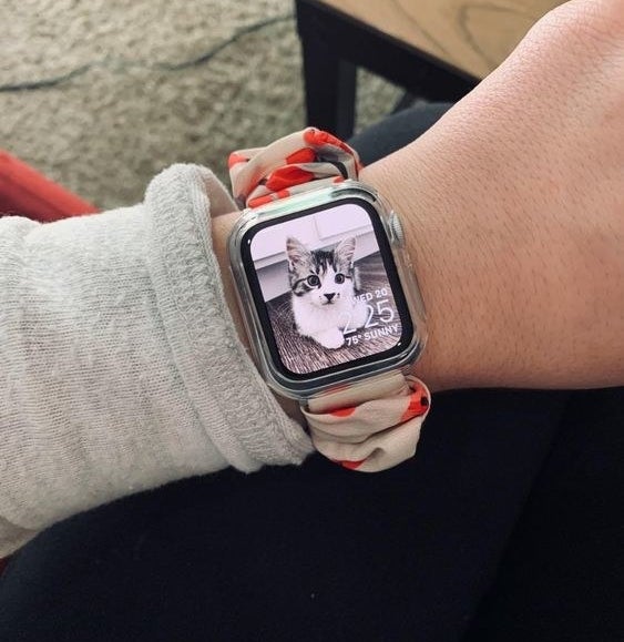 Reviewer wearing the scrunchy Apple Watch band in a white and pink floral pattern