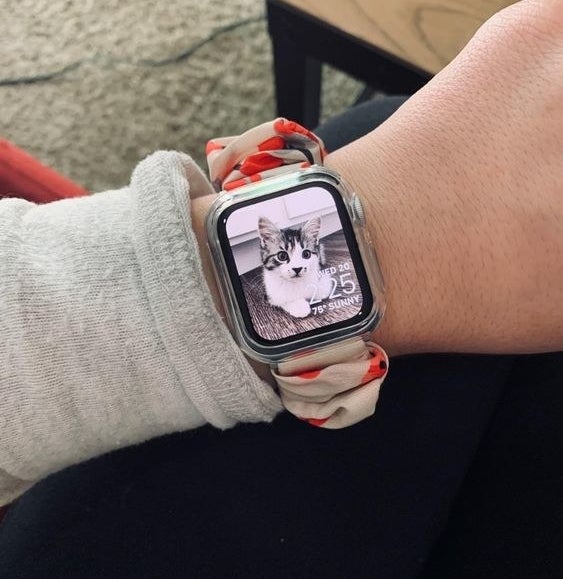 Reviewer wearing the scrunchy Apple Watch band in a white and pink floral pattern
