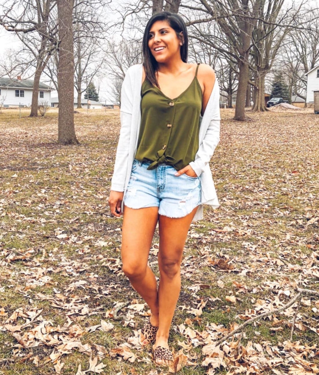 A reviewer wearing the button-up tank in green, styled with denim shorts and a white cardigan