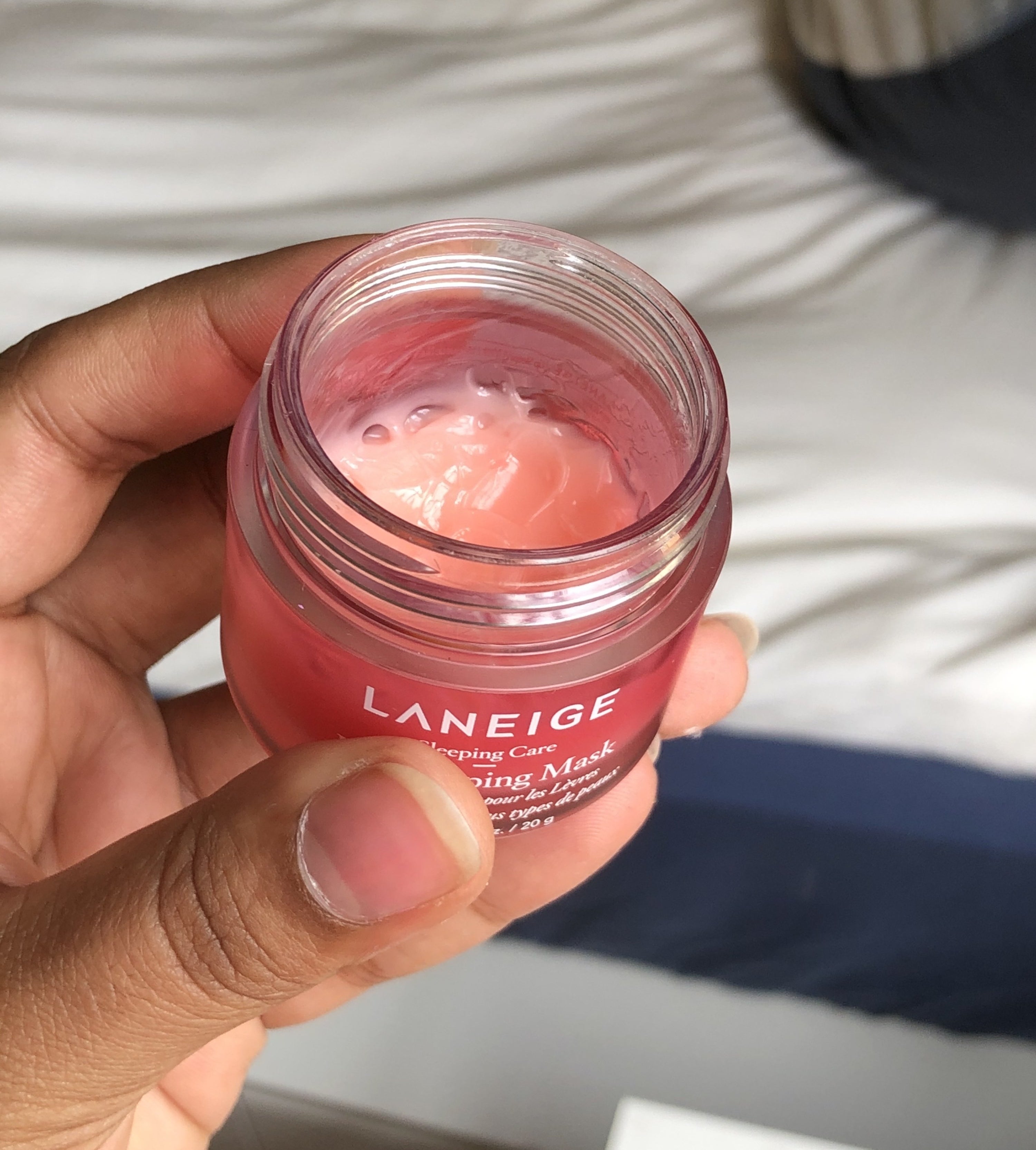 A person holding a small jar with a lip mask inside