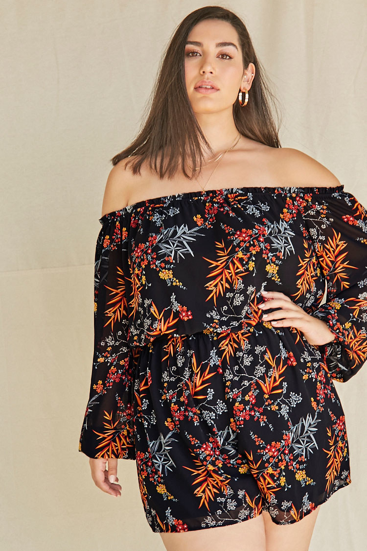  Model wearing the black romper with long peasant sleeves, elastic waist, and orange, red, and white floral pattern