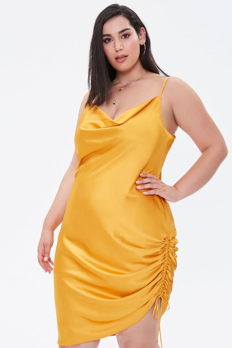 Model wearing yellow dress with side ruched self-tie drawstring and asymmetrical hem