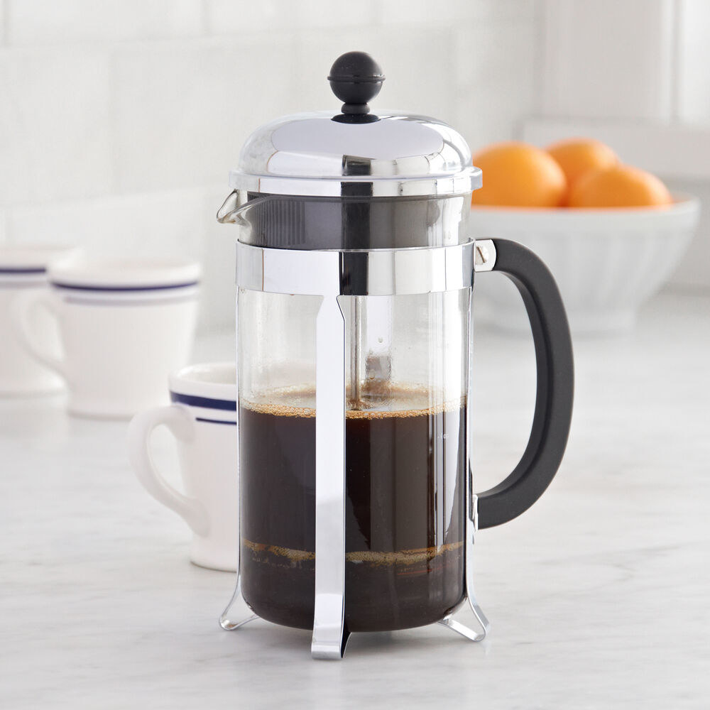 the glass French press with silver accents and a black handle filled with coffee