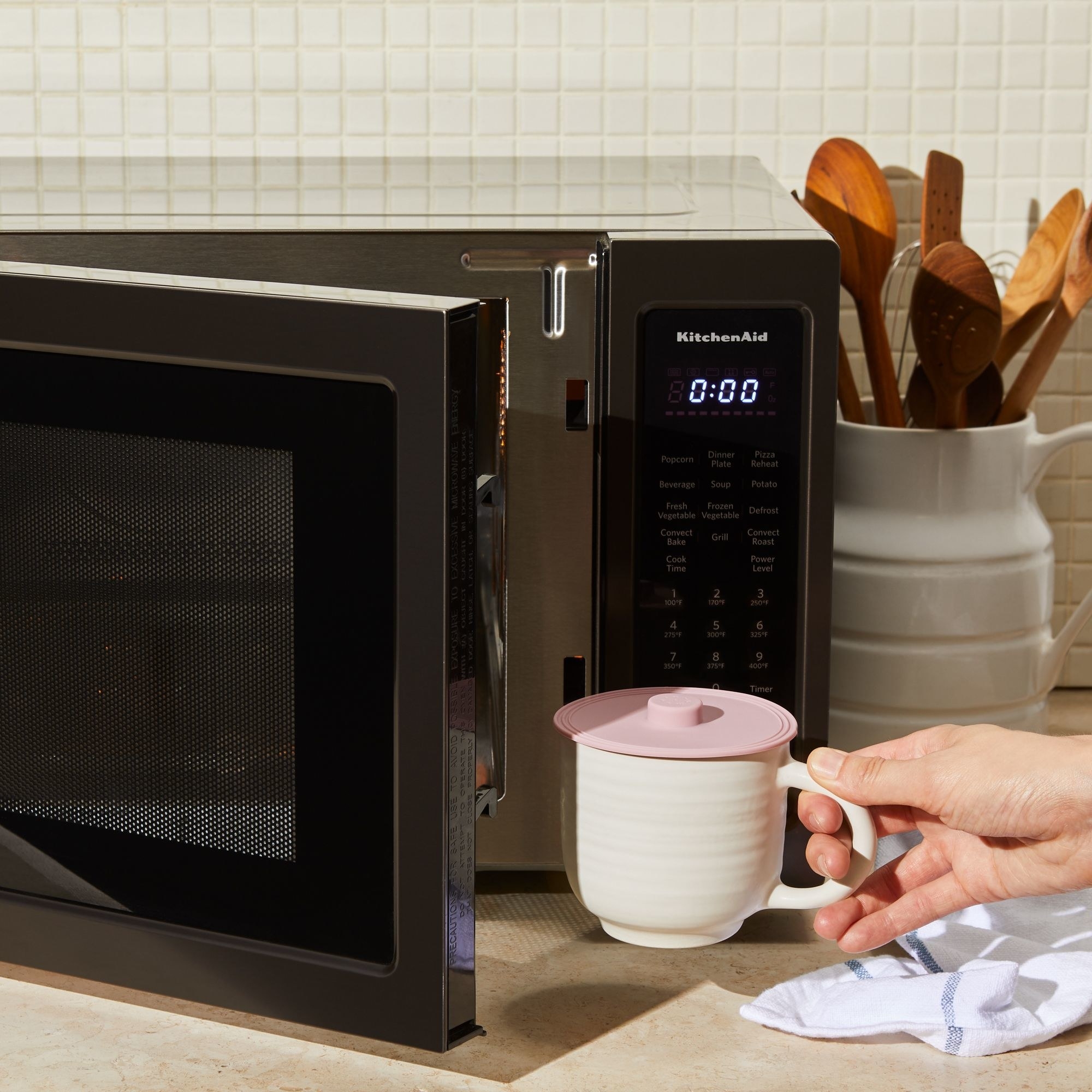 mug with a small pink lid going into a microwave