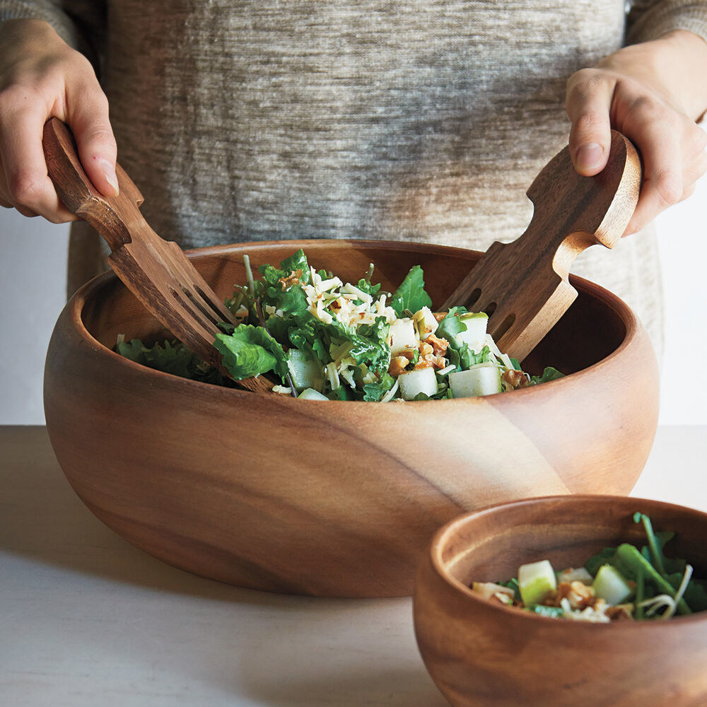 the easy-to-use wooden salad hands (that look like oversized forks) digging into a salad in a big wooden bowl