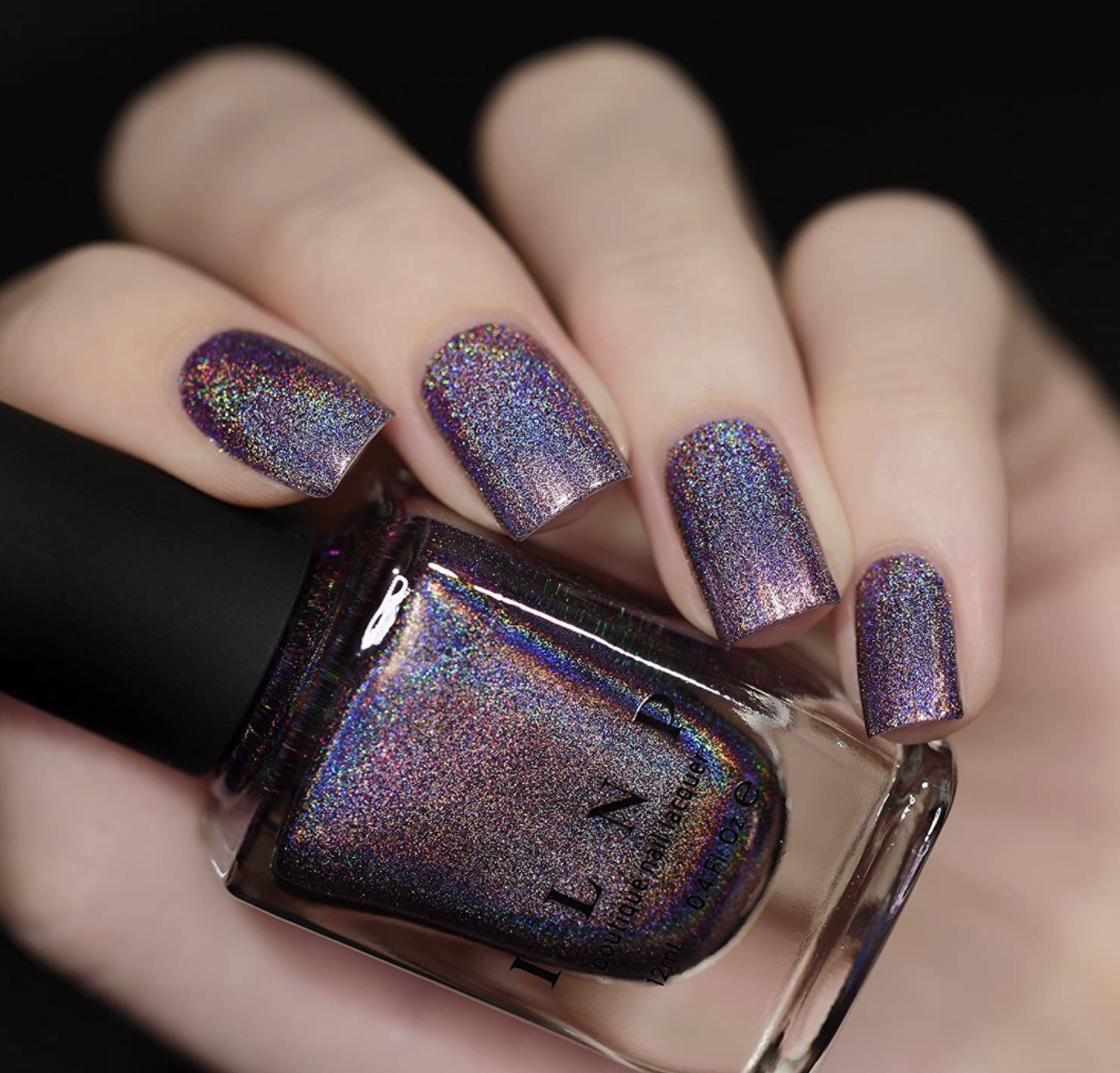 Model wears ILNP Charmed purple holographic nail polish on their hand