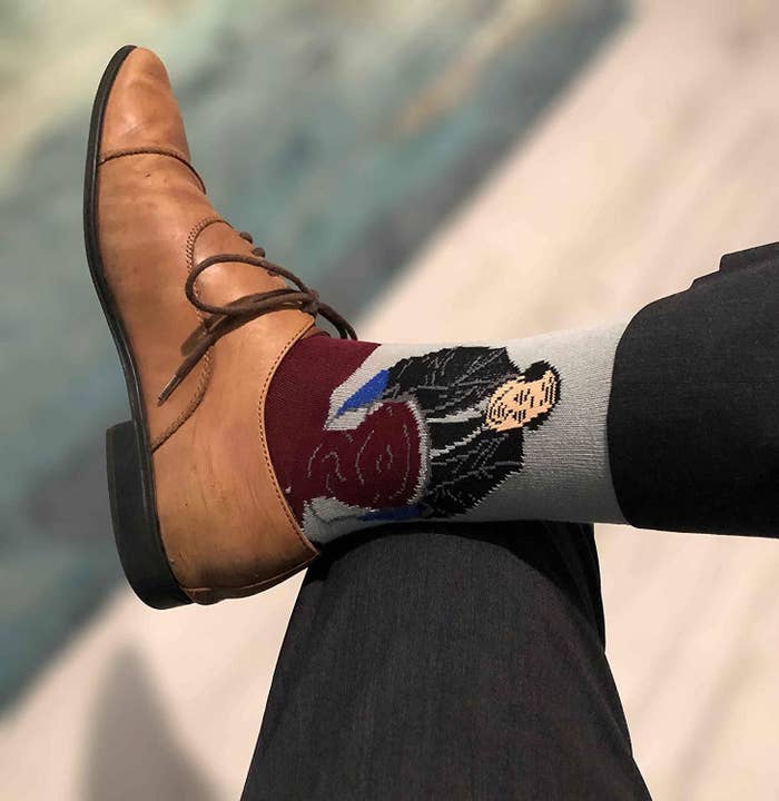 A model wearing the socks peeking out of Oxford shoes. Kevin from &quot;The Office&quot; is on the ankle, and the red chili spilling out covers the foot