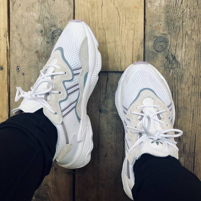 BuzzFeed editor showing the sneakers on feet in a white, tan, and lavender colorway