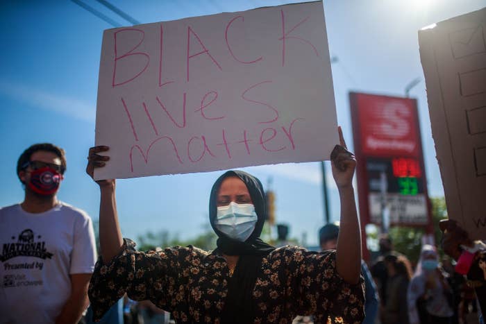 A woman wearing a facemask holds a sign during a protest in Minneapolis on May 29 over the death of George Floyd, a black man who died after a white police officer pinned him on the ground in a neck chokehold until he became unresponsive.