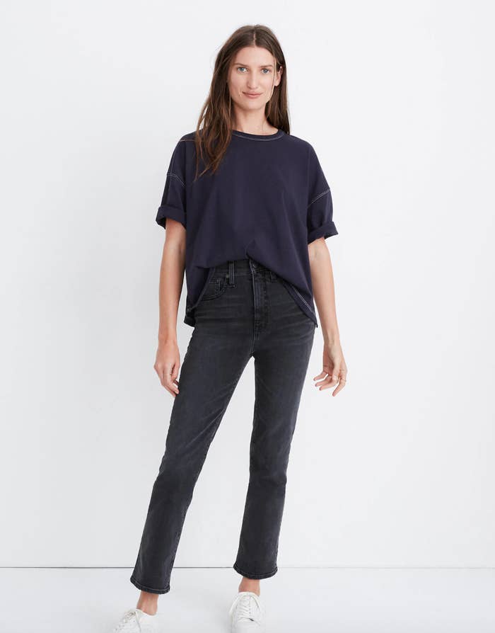 A model in a boxy oversized navy t-shirt with the front tucked into high-waisted jeans 