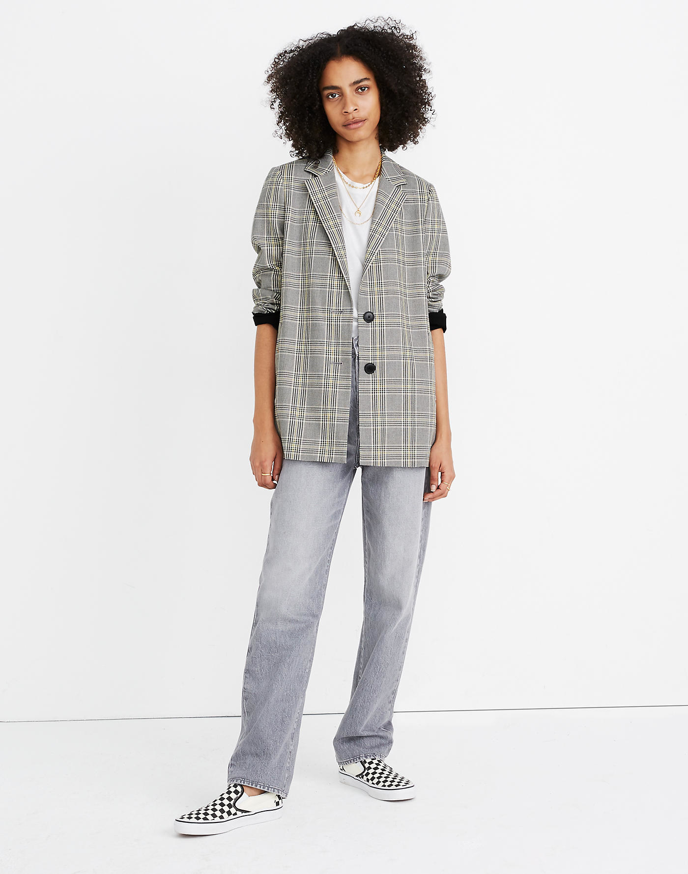 A model in a light gray plaid collared oversized jacket rolled up at the sleeves 