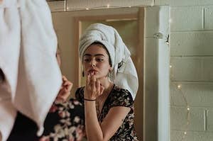 Female applying a beauty product and getting ready in front of a mirror, 