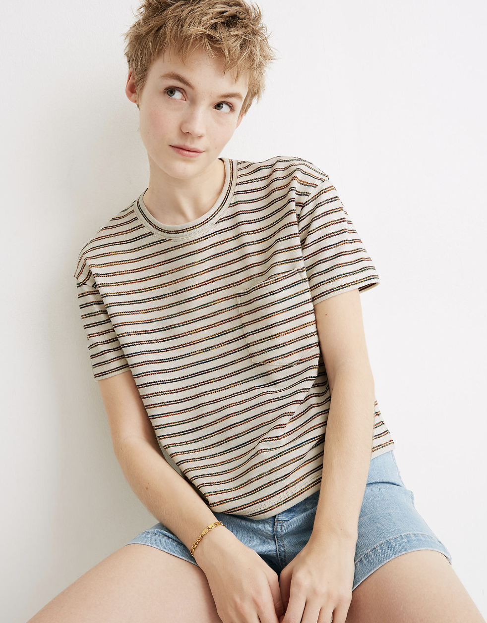 A model in a short-sleeved striped beige tee with a pocket at the left side of the chest 
