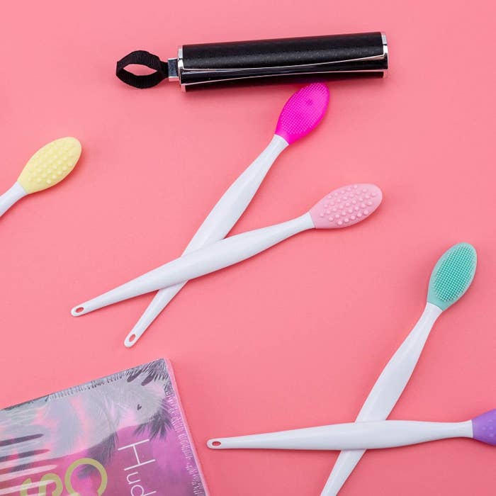 Five lip brushes next to a magazine and lipstick tube