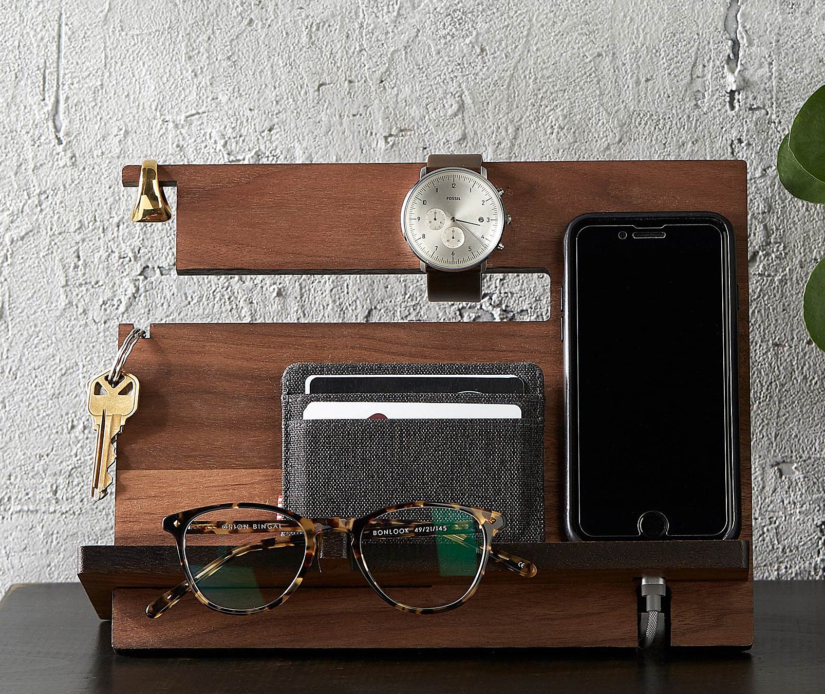 Small items like sunglasses, a phone, keys, and a wallet on a wooden tray