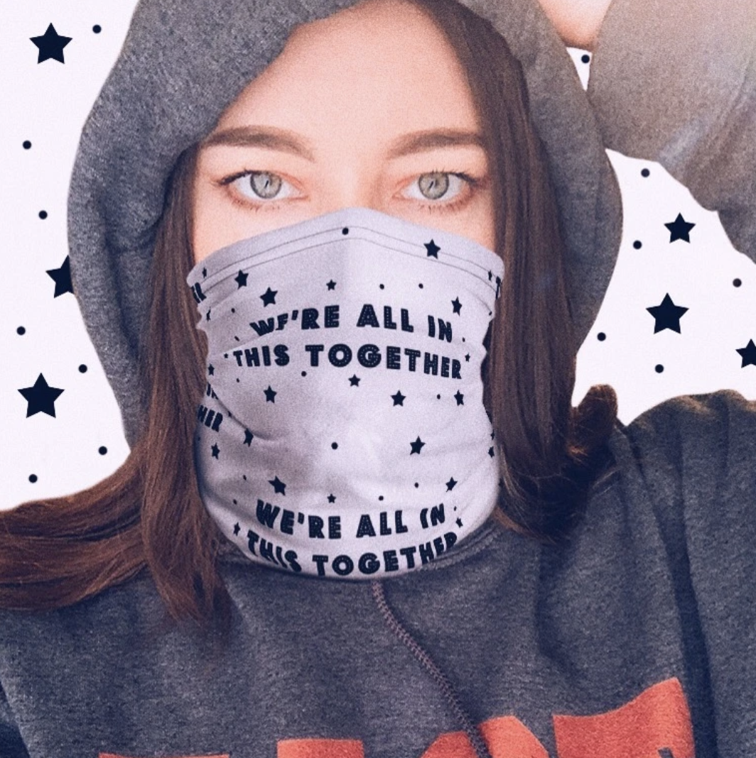 a gray gaitor over a model&#x27;s mouth and nose with stars scattered over it and the saying &quot;we&#x27;re all in this together&quot; repeated throughout the design