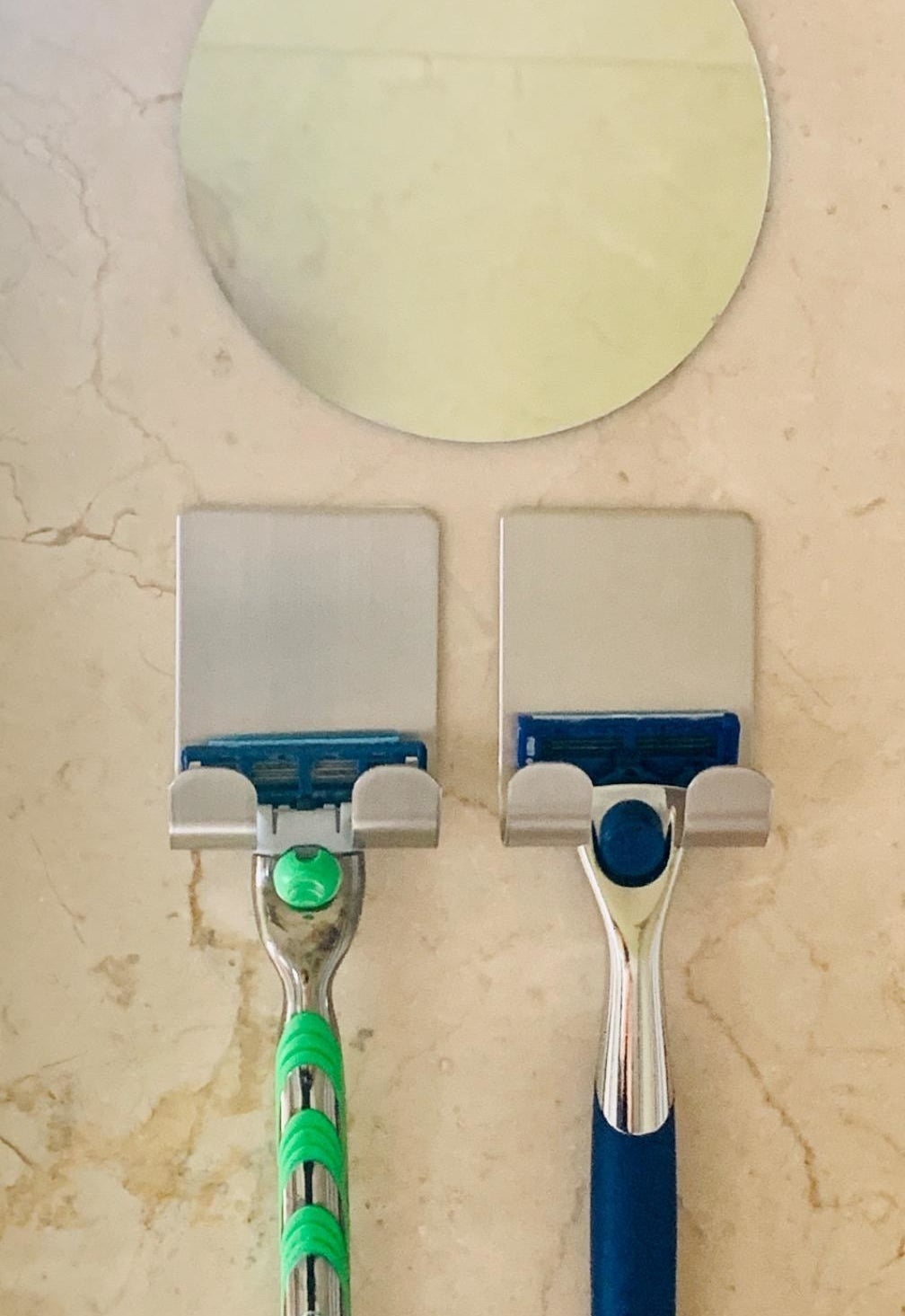 Two razors hanging next to each other on self-adhesive razor holders 