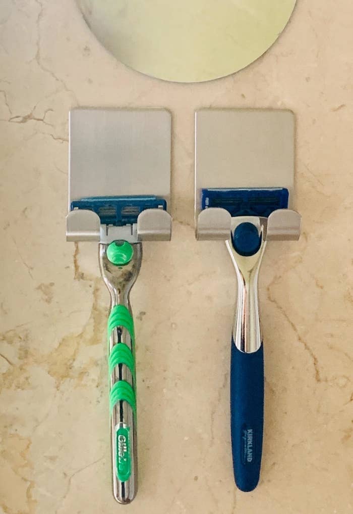 reviewer&#x27;s silver razor holders stuck to a wall with razors on them 