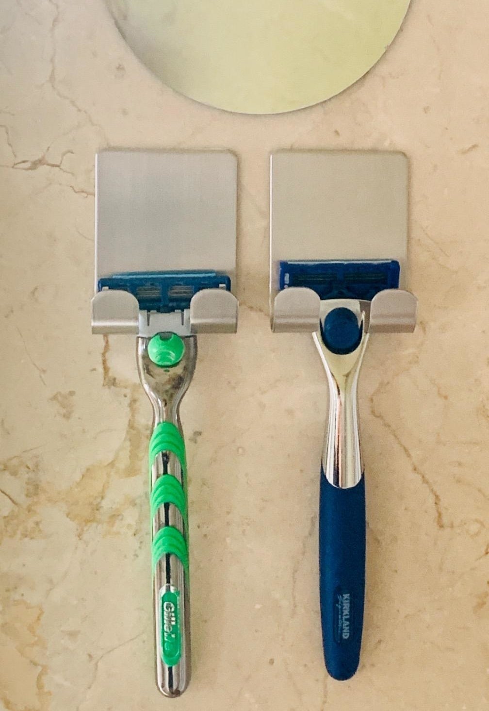 Two razors hanging next to each other on self-adhesive razor holders 