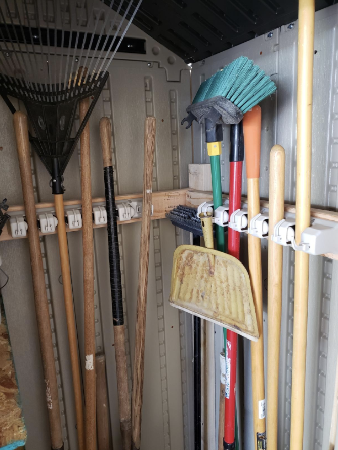 a reviewer photo of two broom organizers alongside the walls of their garage