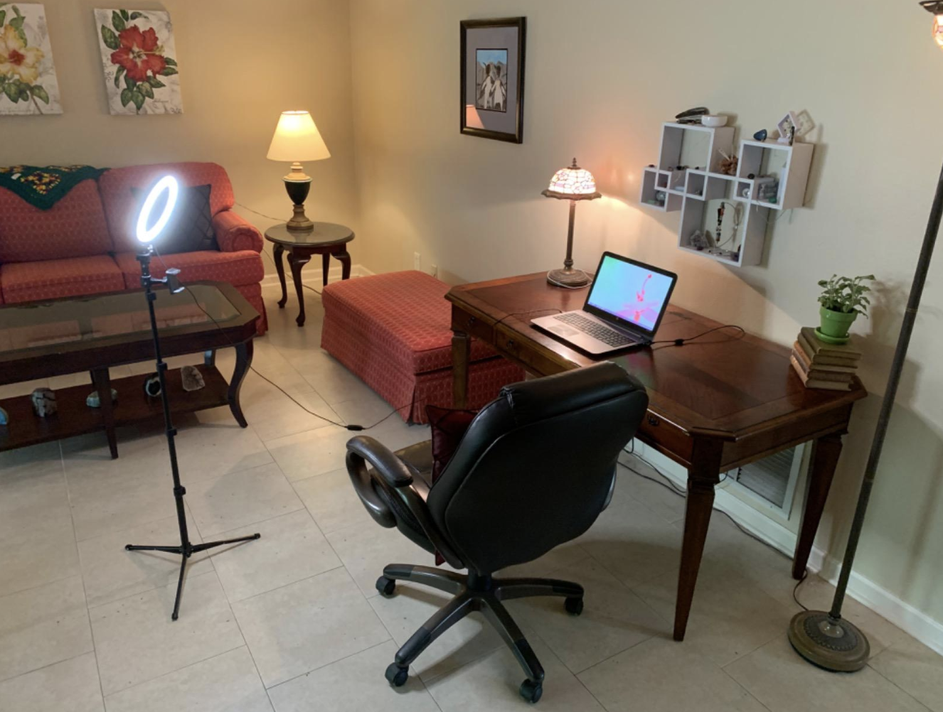 A lit selfie ring on a tripod pointing at a reviewer&#x27;s desk set up 