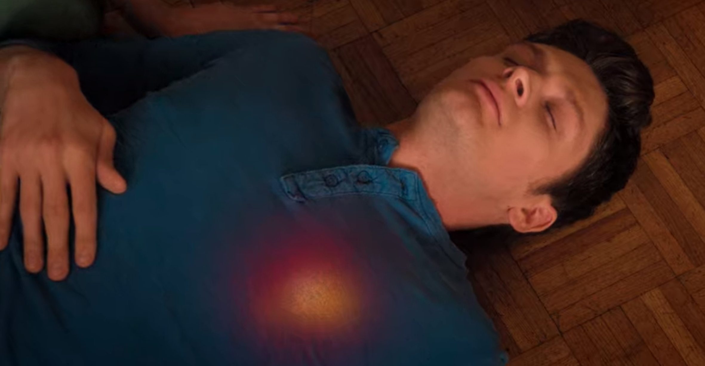A man lies on the ground with his heart area glowing