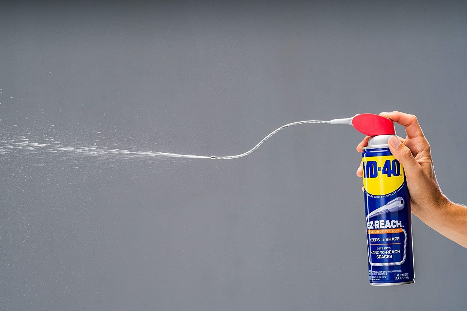 A model&#x27;s handing holding a can of WD-40 and spraying a stream of its contents