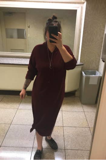 reviewer wearing the burgundy long-sleeve dress knotted at the side