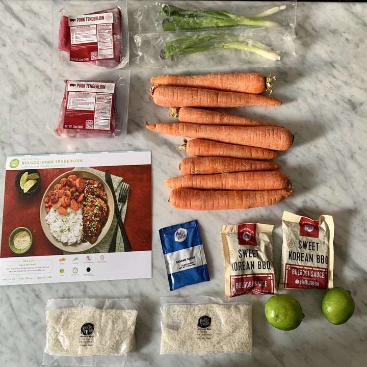 The ingredients for a meal laid out, including carrots rice, sauce, and meat