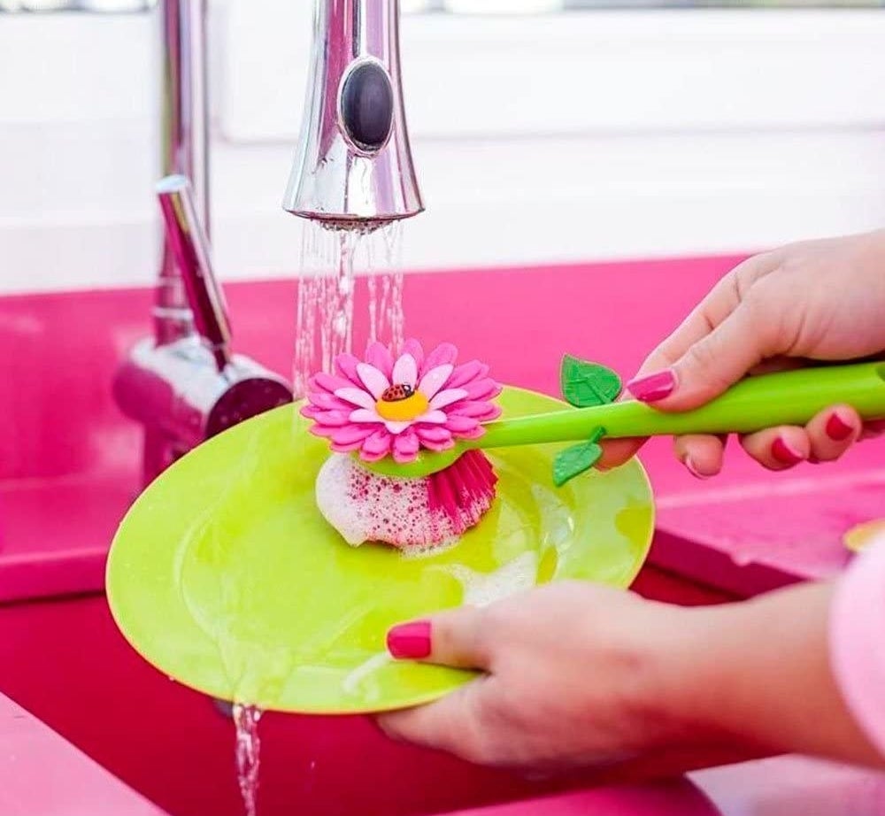 a model using the pink and green flower dish scrubber