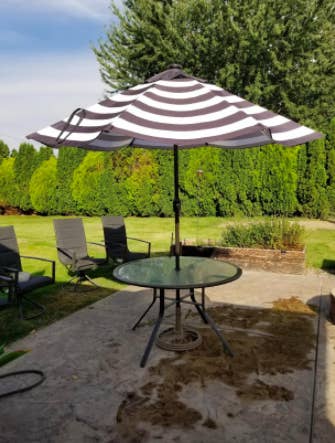 reviewer's patio with round glass table and a striped umbrella on it