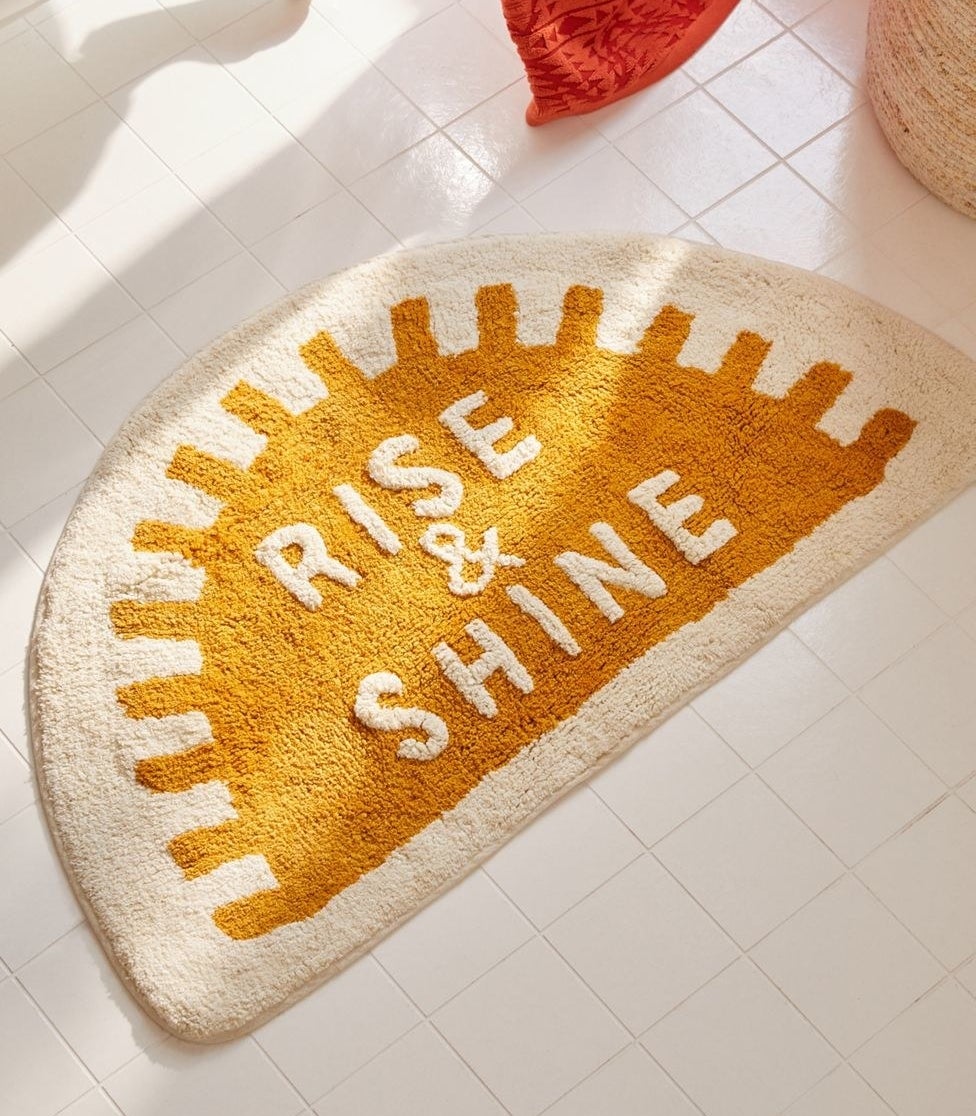 the sun-shaped bath mat with the text &quot;rise &amp;amp; shine&quot;