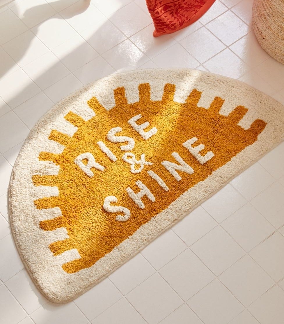 the sun-shaped bath mat with the text "rise & shine"