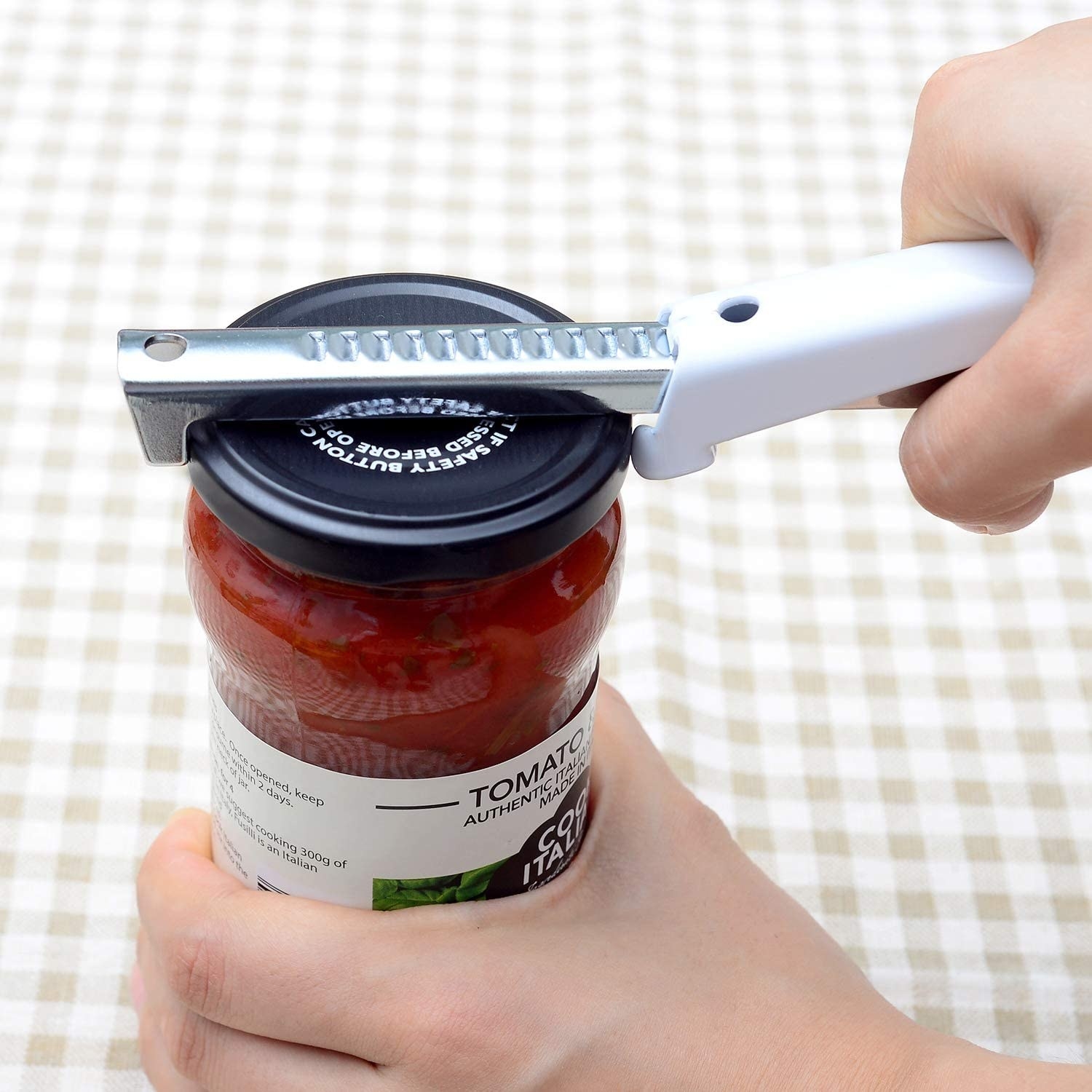 person using the jar opener that latches across the top of the lid and has a handle to move it