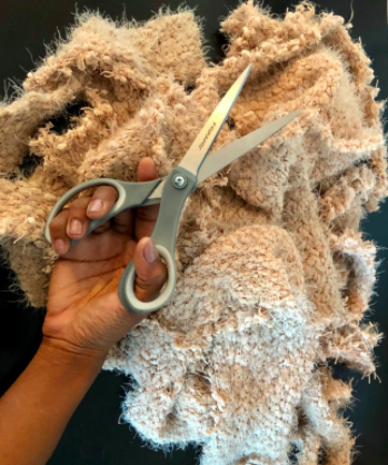 person holding the scissors in front of a bunch of thick fabric they cut with them 