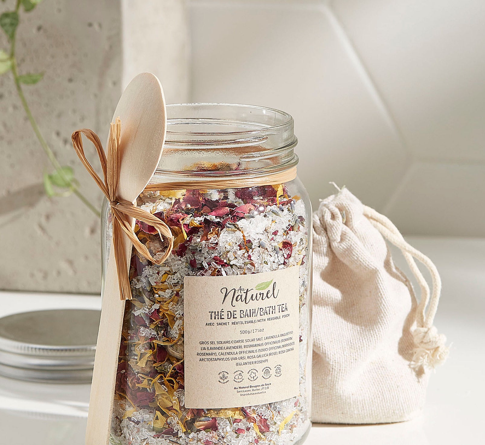 A large jar filled with bath salts There is a small wooden spoon tied around the jar with a string