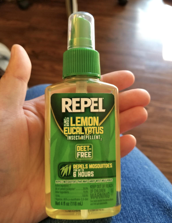 a reviewer's hand holding the bug spray bottle