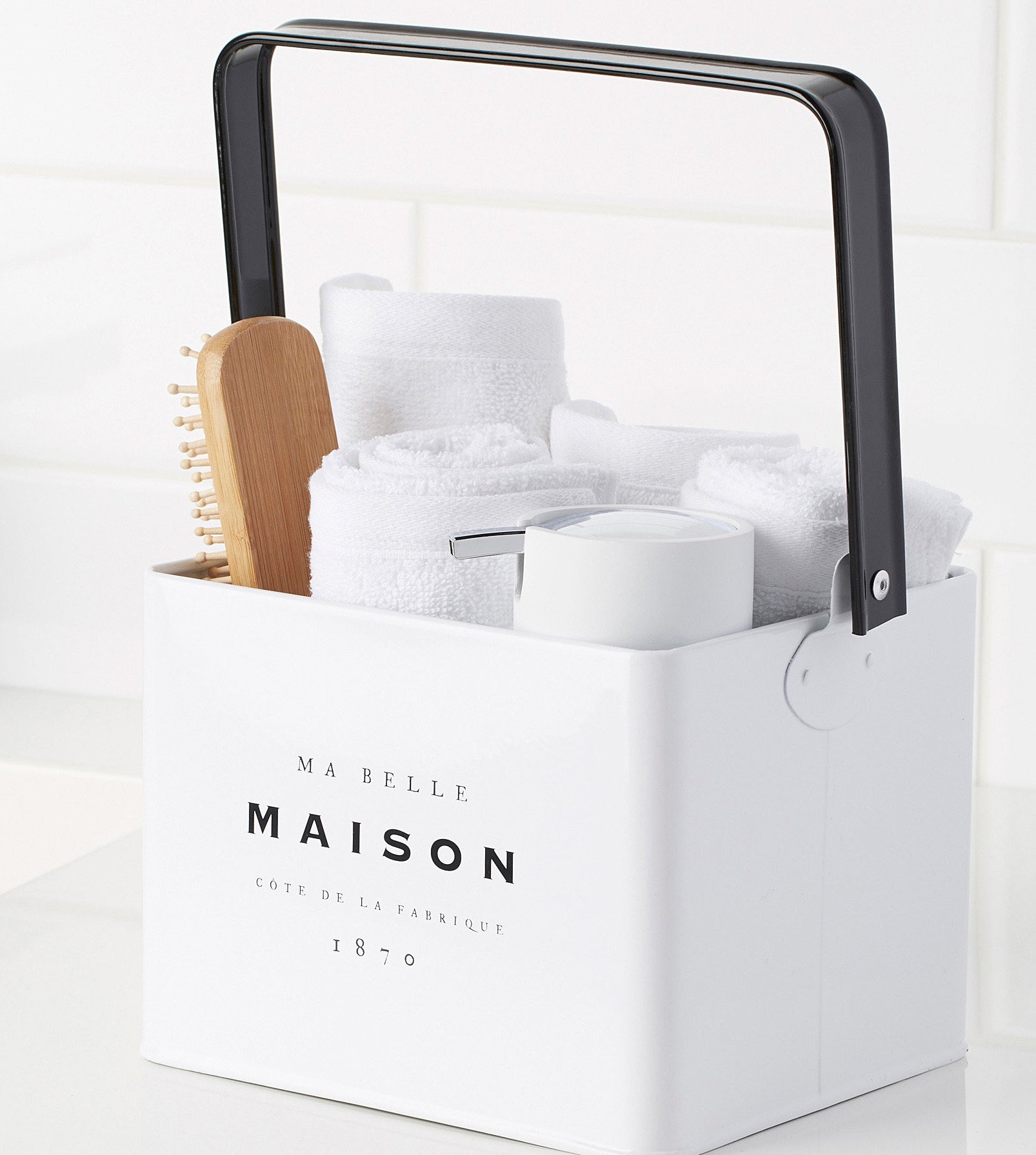 A metal basket filled with bathroom items like towels a soap dispenser and a hairbrush