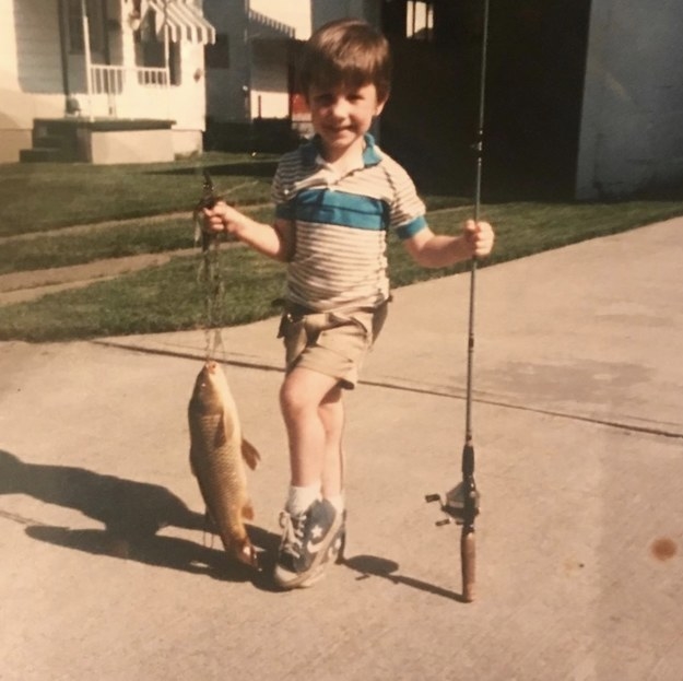 kid posing with a fish with one leg bended in front of the other