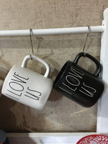 a reviewer photo of a black and white mug hanging from the S-hooks mounted on a tension rod 