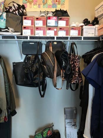 a reviewer photo of several bags and purses hanging from S-hooks that are hanging on a wire shelf in a closet 