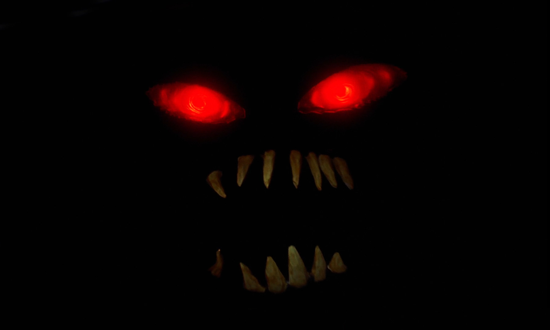 photo of a faceless character with glowing eyes and sharp teeth