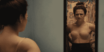 A gif of Jenny Slate in Obvious Child wearing a bra and posing in front of a mirror