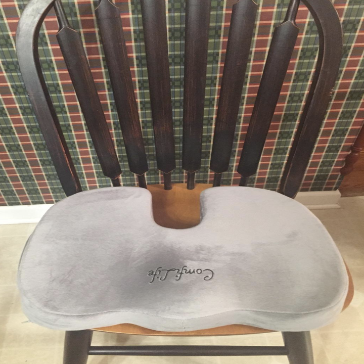 The cushion sitting in a hard, wooden kitchen chair 