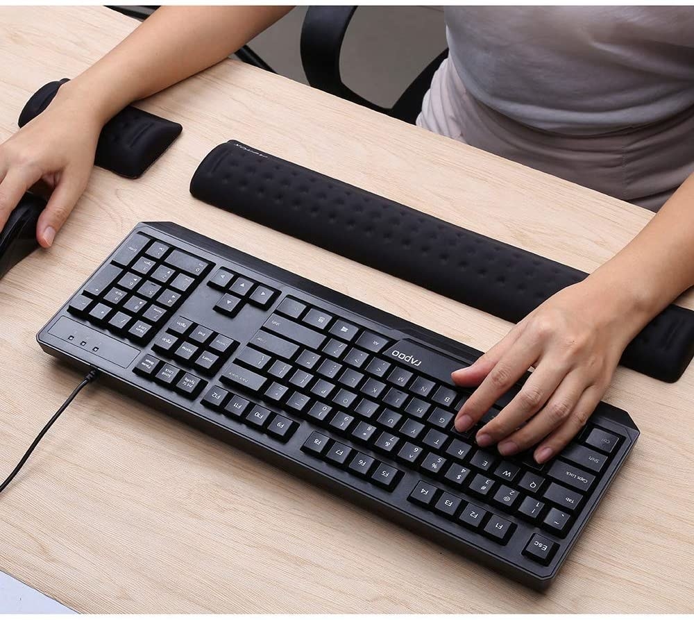 A person with their wrists on the wrist wrests while using a keyboard and mouse