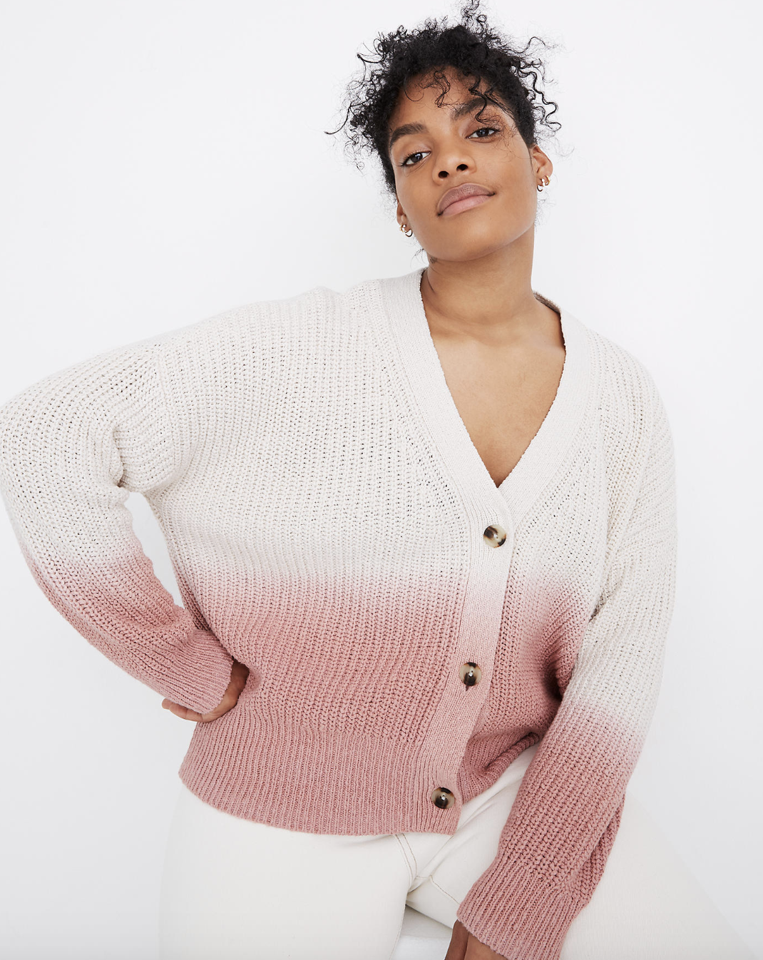 A model in a white knit button-up cardigan with a dip-dyed pink at the bottom of the body and sleeves 