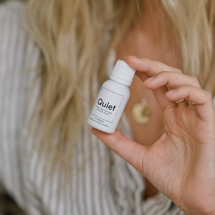 A person holding a small bottle of essential oils labeled quiet